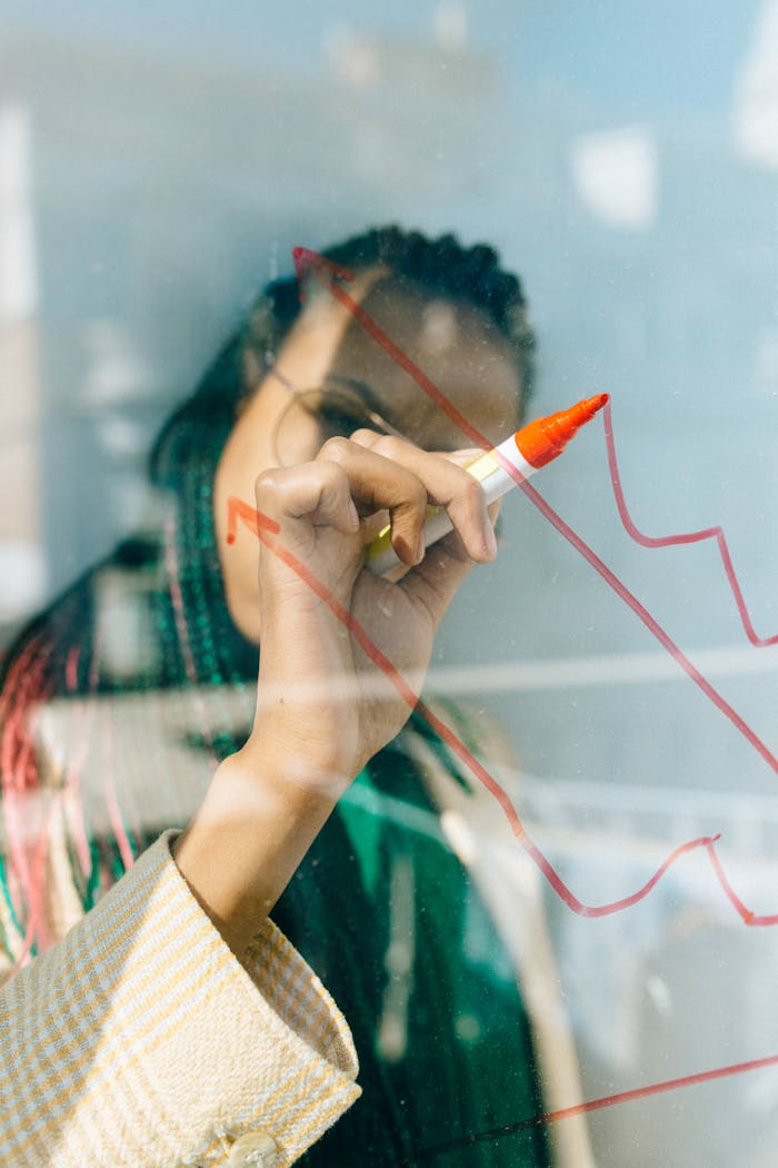 about-us A businesswoman draws a red financial graph on a glass panel, symbolizing strategy and success.